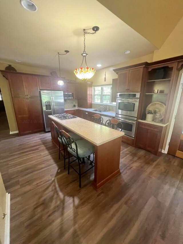 kitchen featuring a center island, a kitchen breakfast bar, dark hardwood / wood-style floors, pendant lighting, and appliances with stainless steel finishes