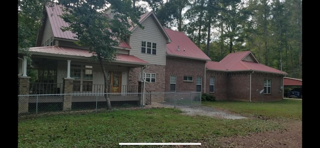 rear view of property featuring a yard and covered porch