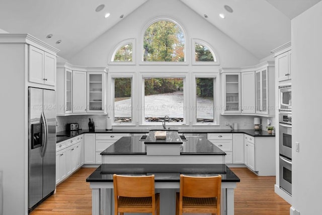 kitchen with white cabinets, appliances with stainless steel finishes, a center island, and a breakfast bar area