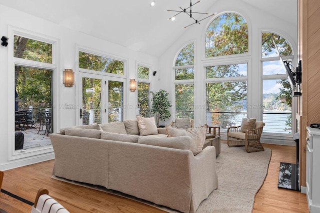 sunroom featuring french doors, vaulted ceiling, and an inviting chandelier