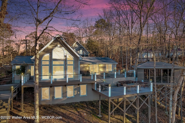 back house at dusk featuring a deck