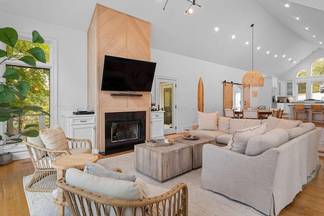 living room featuring a large fireplace, light hardwood / wood-style flooring, and high vaulted ceiling