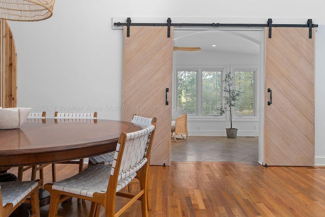 dining room with a barn door and hardwood / wood-style floors