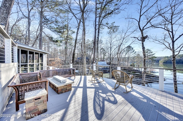 wooden terrace featuring a water view, a fire pit, and a sunroom