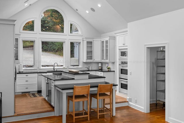 kitchen featuring white cabinetry, sink, stainless steel appliances, dark hardwood / wood-style floors, and a kitchen island