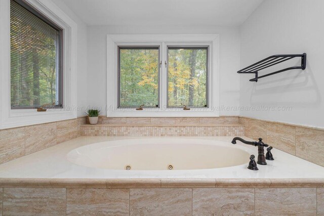 bathroom featuring a relaxing tiled tub and a wealth of natural light