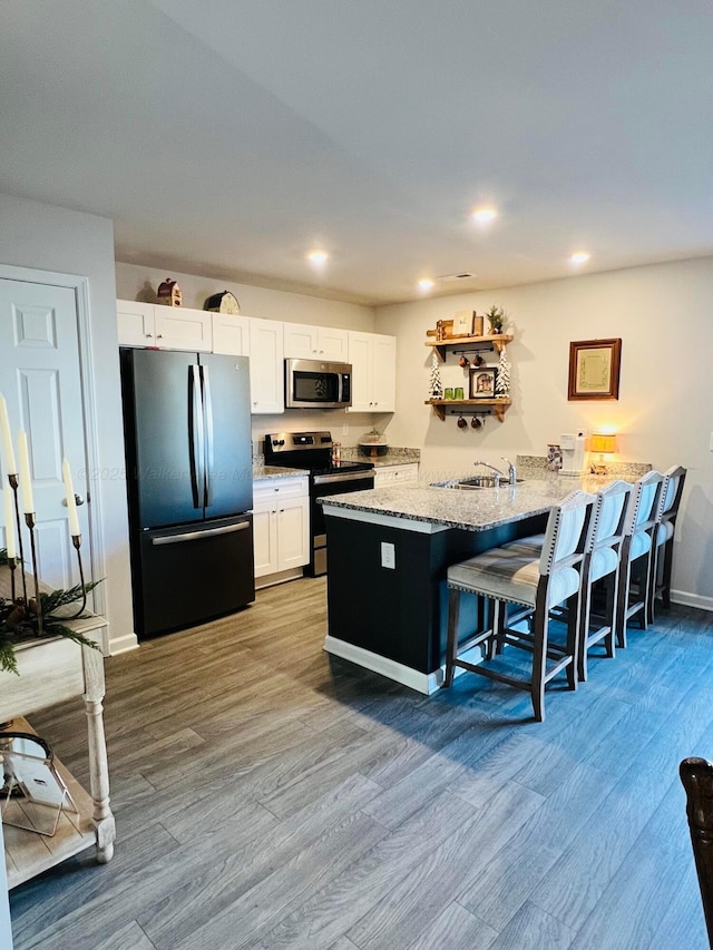 kitchen featuring black fridge, white cabinetry, a breakfast bar area, and electric range oven