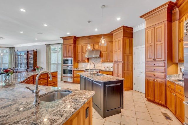 kitchen featuring a kitchen island with sink, plenty of natural light, light stone countertops, and appliances with stainless steel finishes