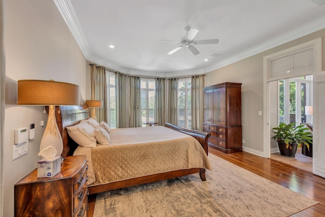 bedroom featuring multiple windows, ceiling fan, wood-type flooring, and ornamental molding