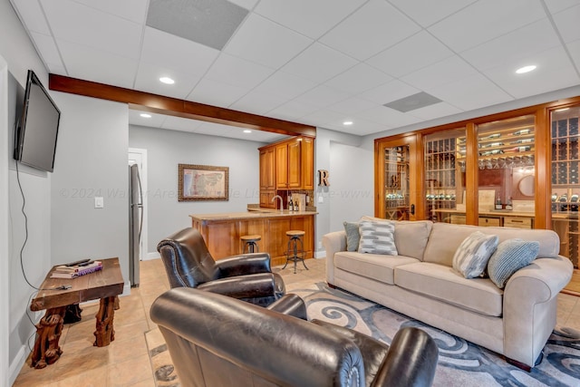 tiled living room featuring a drop ceiling and indoor bar