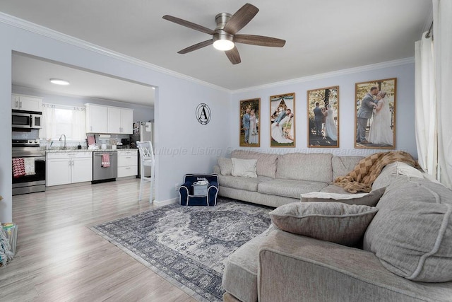 living room featuring crown molding, sink, ceiling fan, and light hardwood / wood-style floors