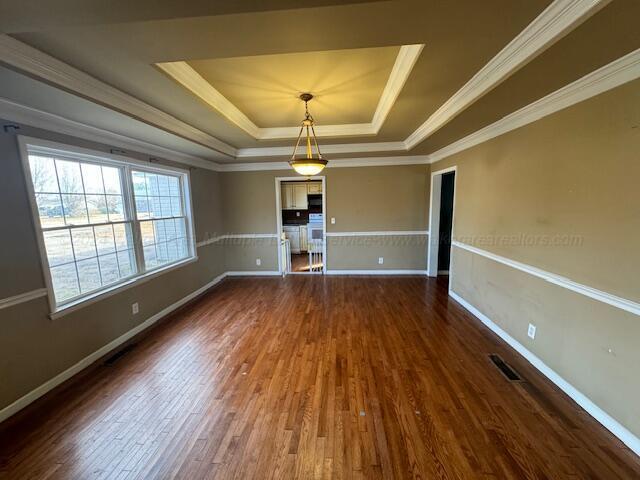 spare room with a raised ceiling, crown molding, and dark wood-type flooring