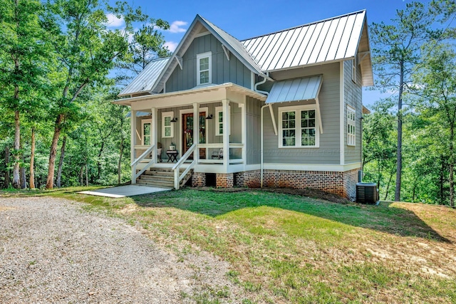 view of front of property with metal roof, a porch, board and batten siding, a front lawn, and a standing seam roof