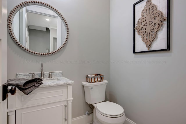 bathroom featuring baseboards, vanity, and toilet