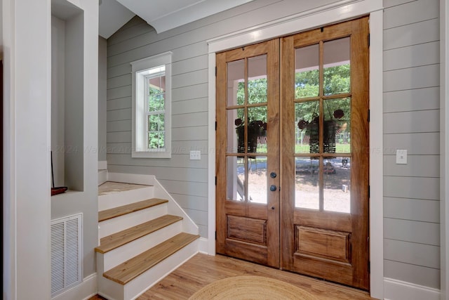 entryway with french doors, wood walls, light wood-type flooring, and visible vents