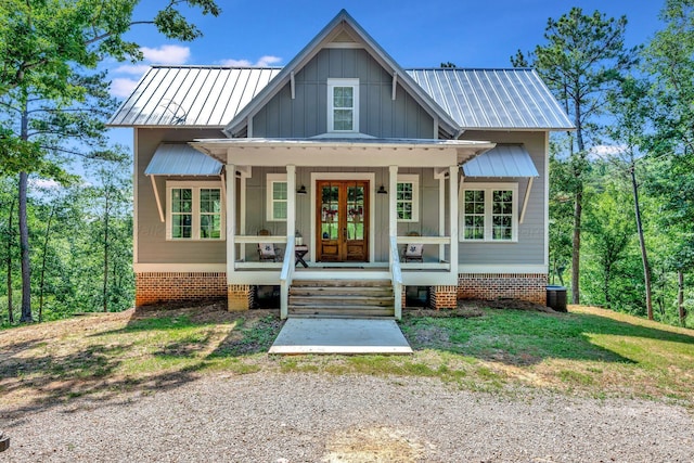 view of front of house with board and batten siding, french doors, metal roof, and a porch