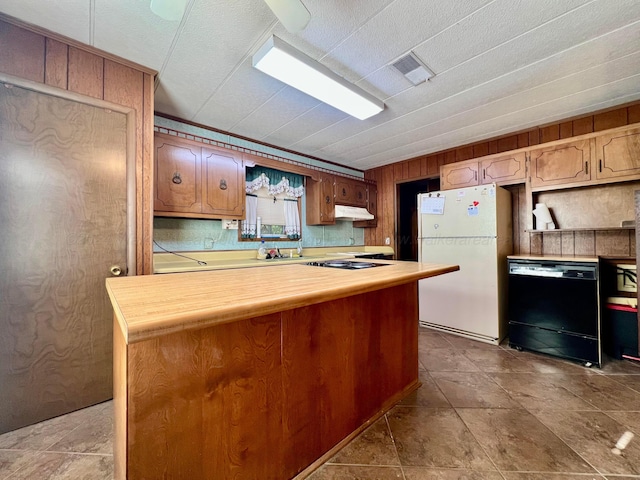 kitchen featuring dishwasher, white fridge, and wood walls