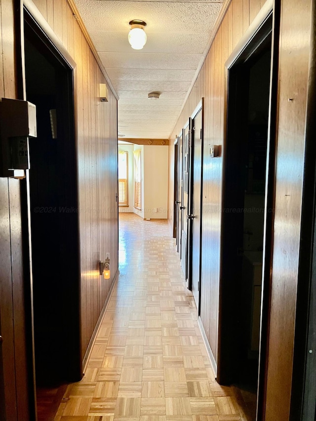 hallway with wood walls and light parquet flooring