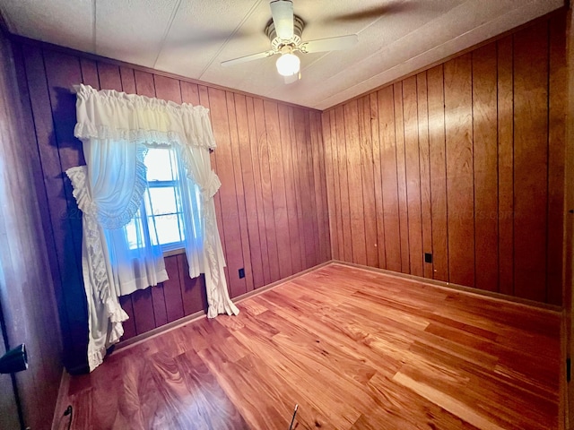 spare room with wood walls, ceiling fan, and wood-type flooring