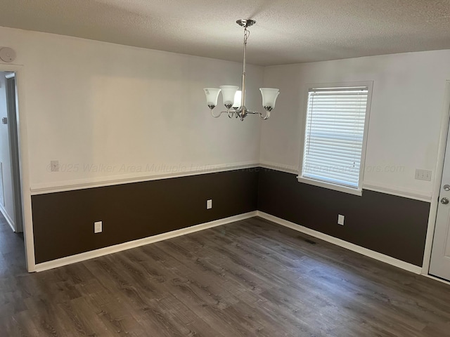 spare room with a chandelier, baseboards, a textured ceiling, and wood finished floors