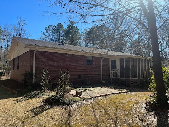 back of house featuring a patio area, brick siding, and a sunroom