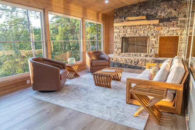 sunroom featuring a stone fireplace and wood ceiling