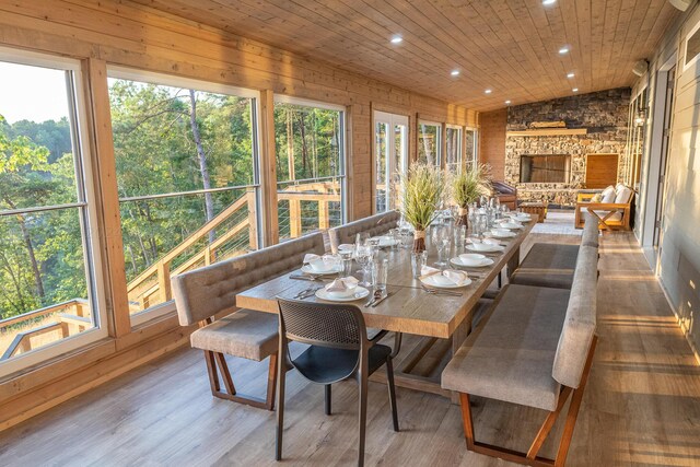 sunroom with a fireplace, wooden ceiling, a healthy amount of sunlight, and vaulted ceiling