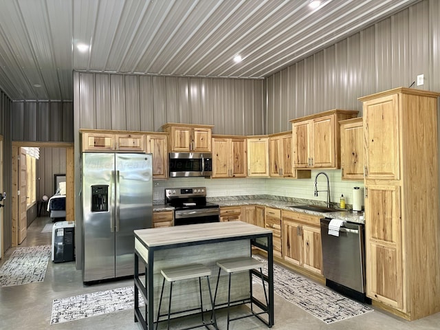 kitchen with a towering ceiling, sink, a kitchen island, stainless steel appliances, and light brown cabinets