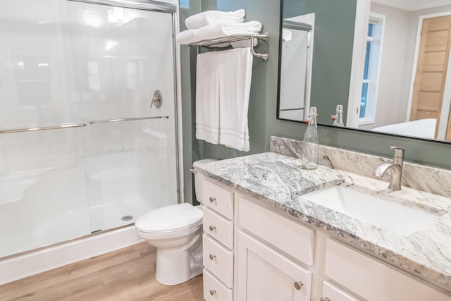 bathroom featuring hardwood / wood-style floors, toilet, a shower with shower door, and vanity