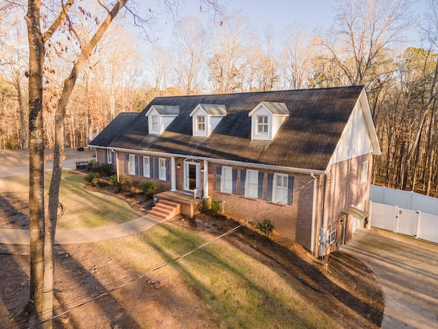 cape cod home featuring a front lawn