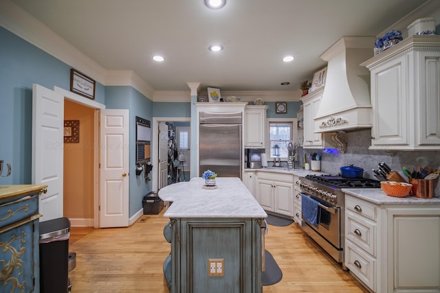 kitchen featuring white cabinets, a kitchen island, custom range hood, and premium appliances