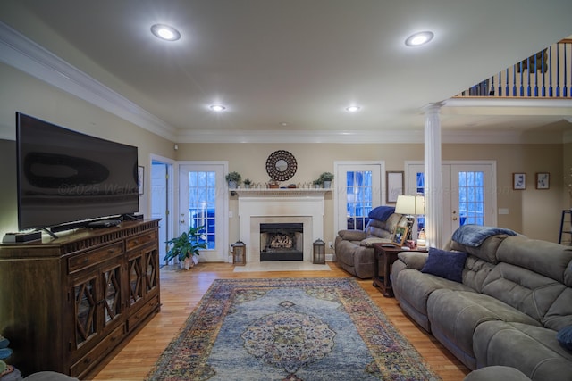 living room featuring light wood-type flooring, crown molding, and decorative columns