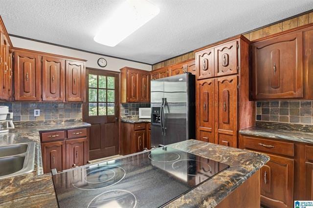 kitchen with decorative backsplash, stainless steel fridge with ice dispenser, a textured ceiling, and black electric cooktop