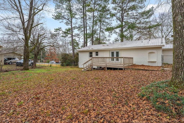 back of house featuring brick siding, fence, a wooden deck, french doors, and metal roof