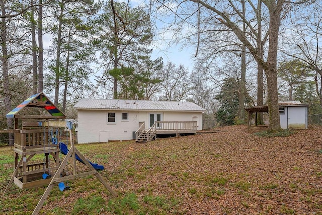 rear view of house featuring metal roof, an outdoor structure, a deck, and a playground