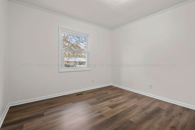 spare room featuring dark wood finished floors, visible vents, baseboards, and ornamental molding