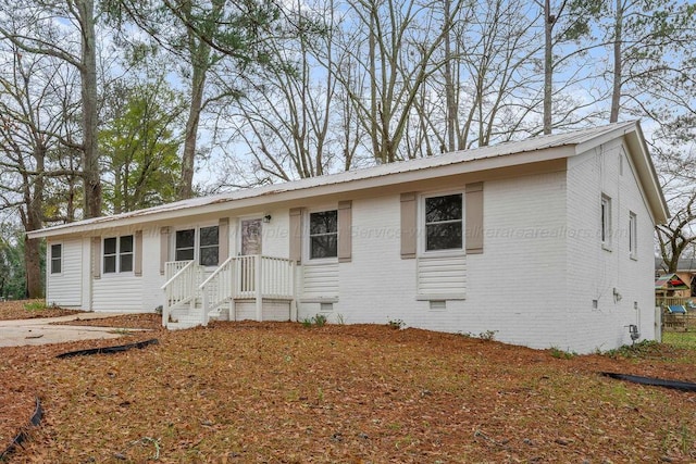 ranch-style home featuring crawl space, brick siding, and metal roof