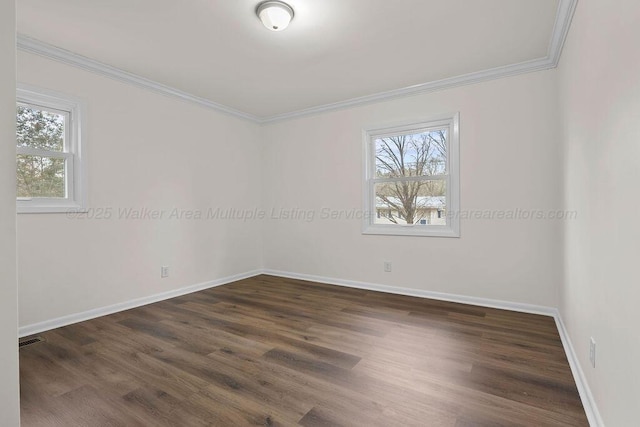 spare room featuring visible vents, baseboards, dark wood-type flooring, and ornamental molding