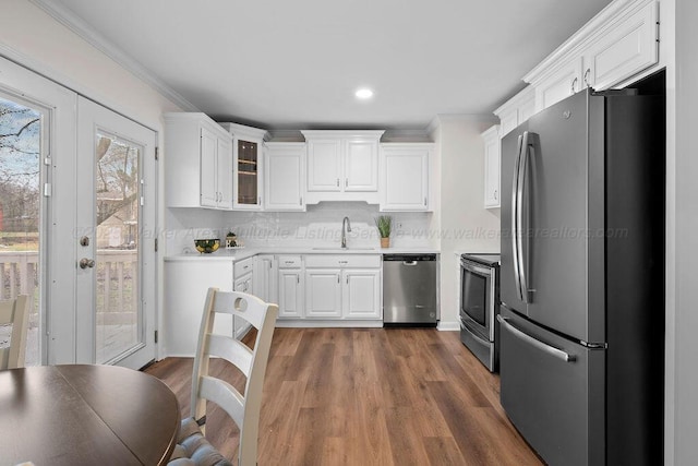 kitchen with white cabinetry, crown molding, appliances with stainless steel finishes, and a sink