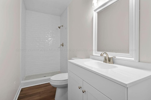 bathroom featuring vanity, toilet, wood finished floors, and a shower stall