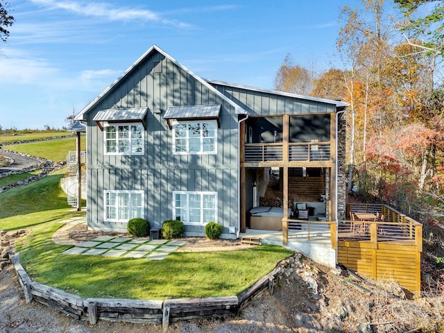 back of property featuring a lawn, a patio area, a balcony, and a hot tub