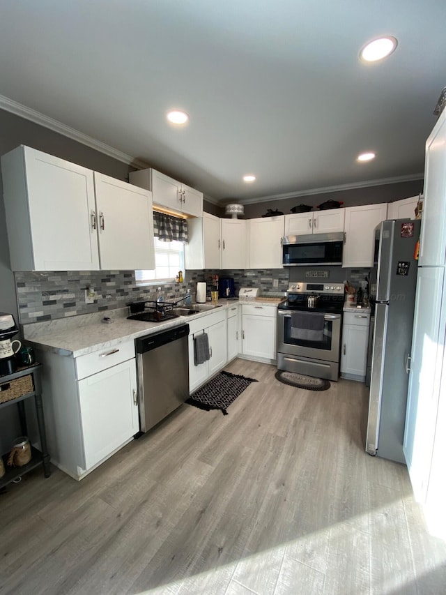 kitchen featuring white cabinetry, crown molding, light hardwood / wood-style floors, and appliances with stainless steel finishes