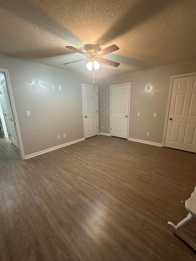 unfurnished room with baseboards, a textured ceiling, a ceiling fan, and dark wood-style flooring