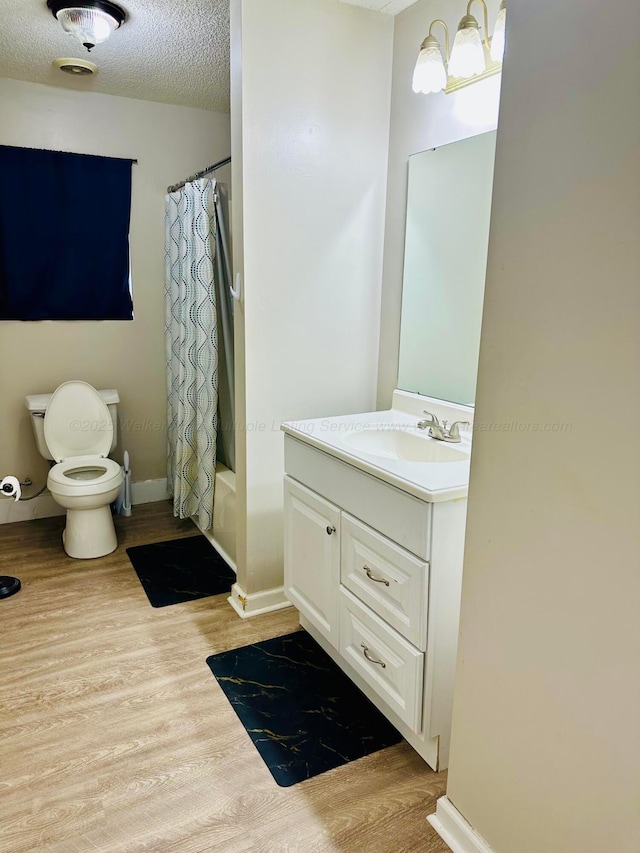 bathroom with shower / tub combo, toilet, wood finished floors, a textured ceiling, and vanity