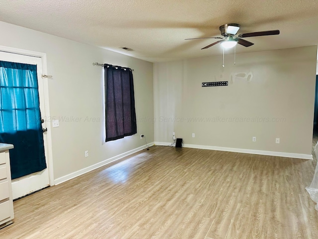 unfurnished room with visible vents, baseboards, light wood-style flooring, and a textured ceiling