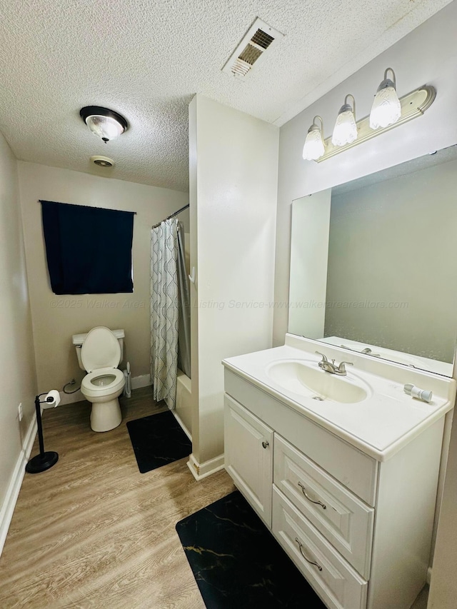 bathroom featuring visible vents, toilet, wood finished floors, shower / bath combo with shower curtain, and vanity