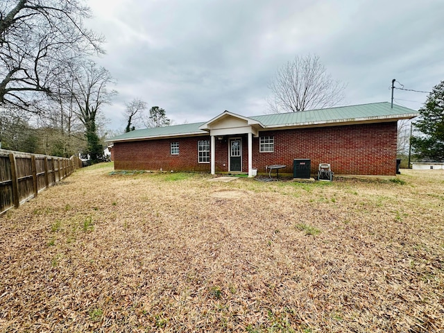 rear view of house with a yard, central AC, fence, and brick siding