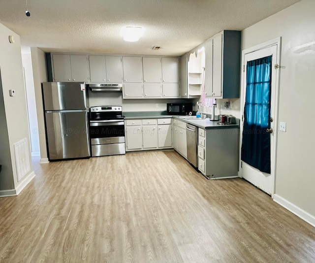 kitchen featuring light wood finished floors, visible vents, stainless steel appliances, a textured ceiling, and under cabinet range hood