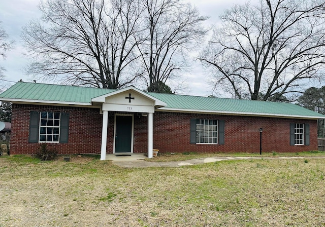 ranch-style home with metal roof, a front lawn, and brick siding