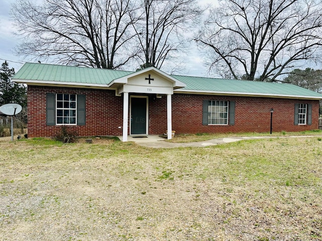 single story home with brick siding, metal roof, and a front yard